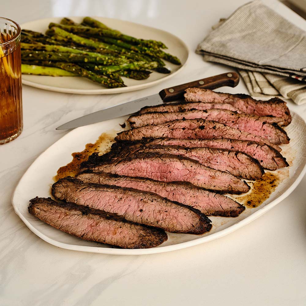 Grilled flank steak on white serving plate