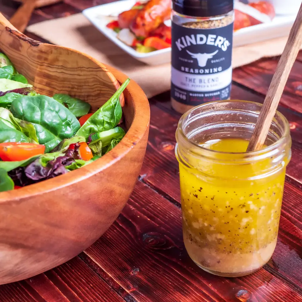 Glass jar of salad dressing next to a bowl of salad