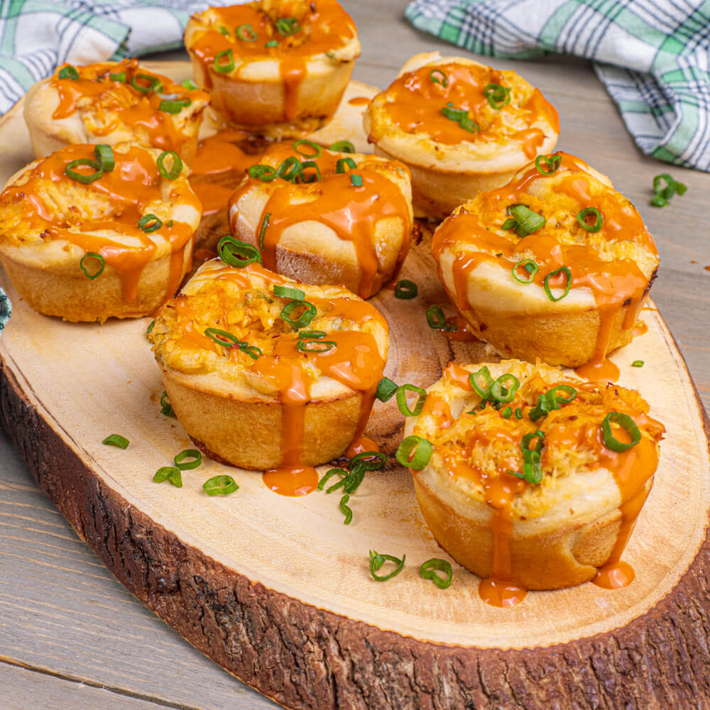 Baked buffalo sauce pulled chicken sliders on a cutting board