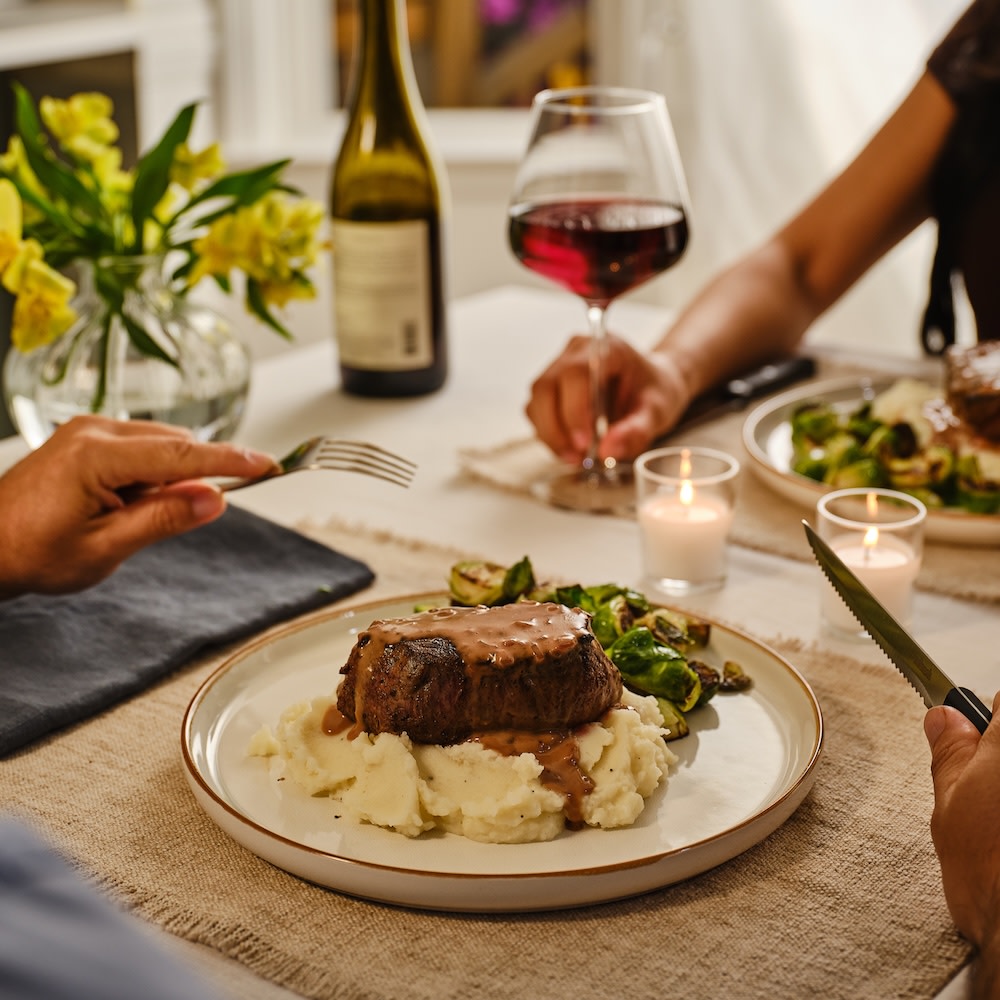 Couple eating filet mignon with mashed potatoes at the table