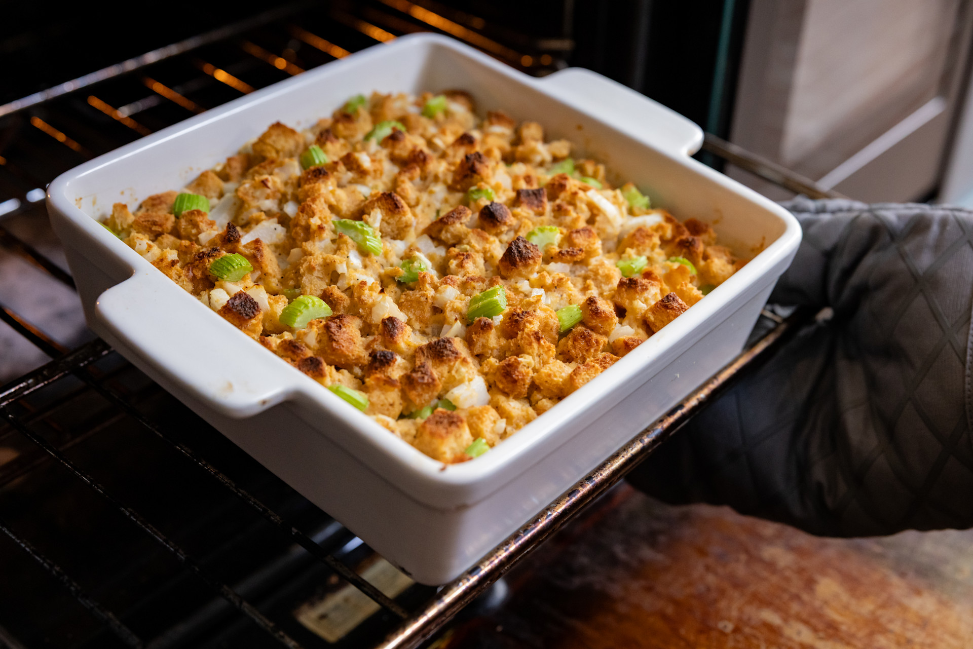 stuffing in a white casserole dish being placed into the oven