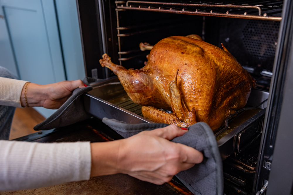 whole turkey on a baking pan being put into the oven