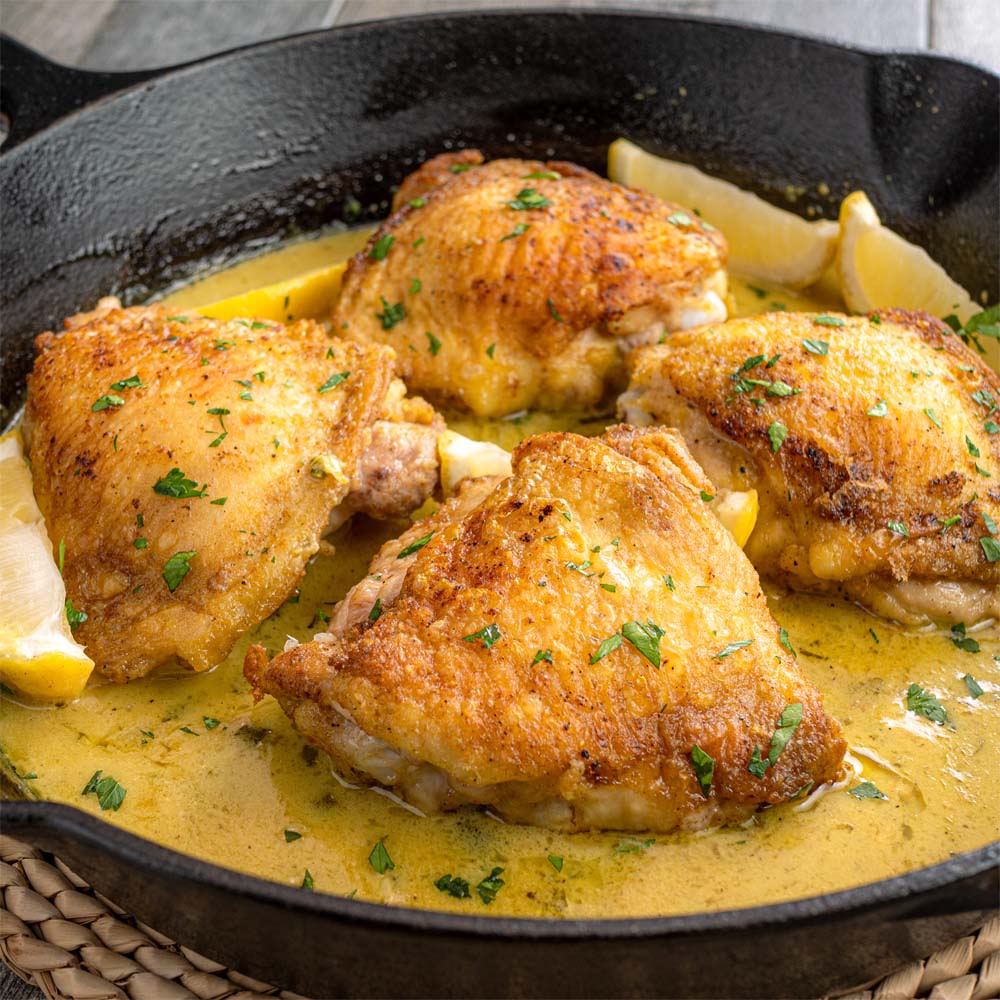 Roasted chicken thighs in a cast iron skillet with sauce