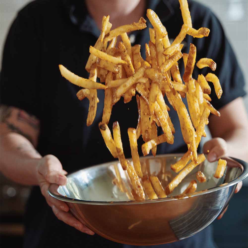 French Fries being tossed in seasoning