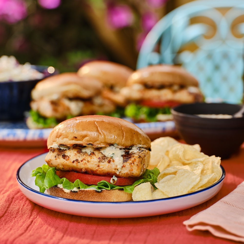 Grilled fish sandwich on a plate with potato chips 