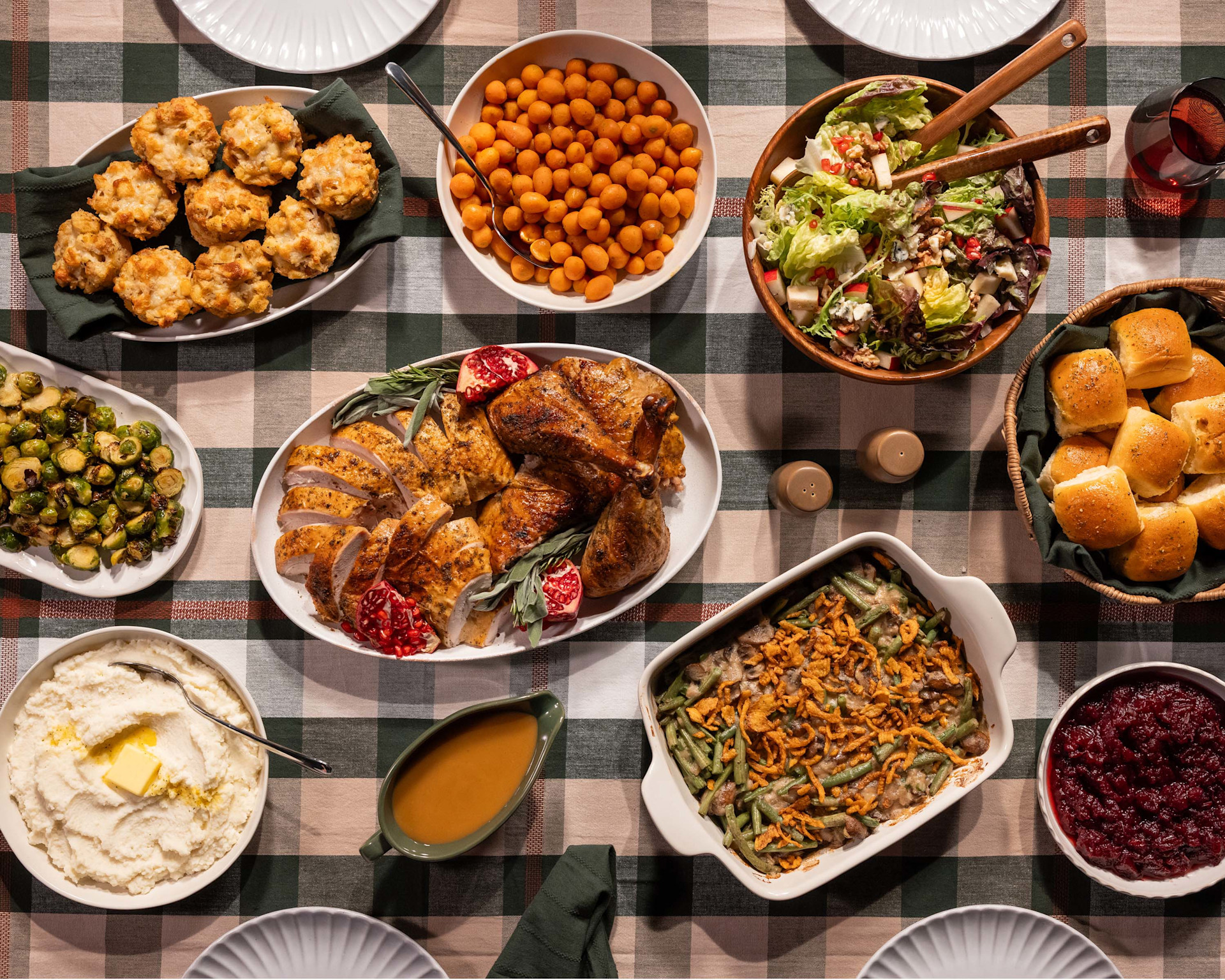 Thanksgiving table with carved turkey and sides on a plaid table cloth