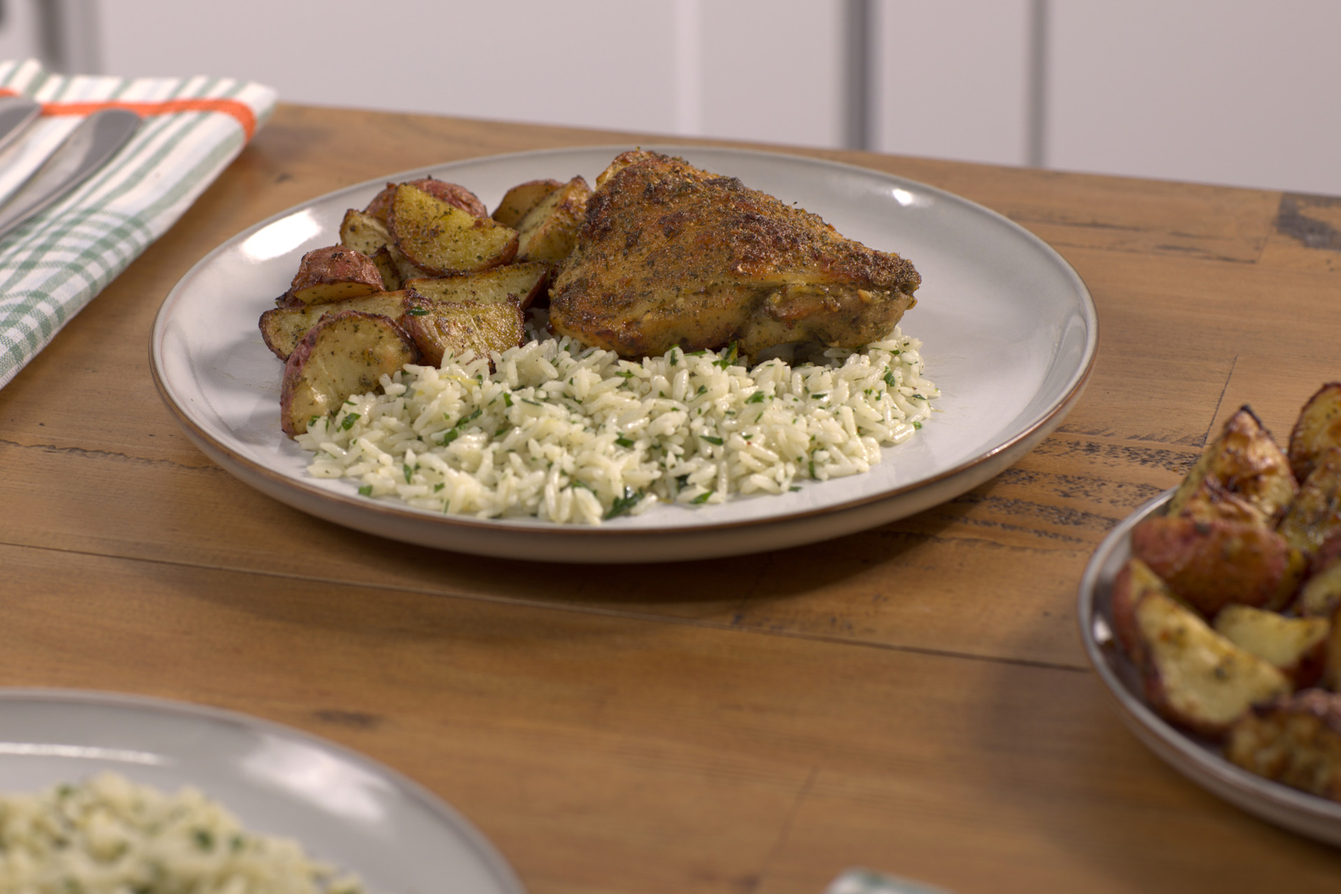 Buttery Garlic & Herb Chicken Thighs with Roasted Potatoes & Lemony Herb Rice on a white plate