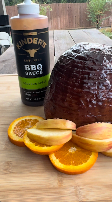 Video still of Kinder's Burbon Apple BBQ sauce, cooked ham, apples, and oranges