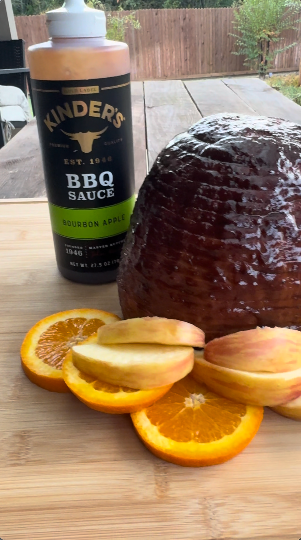 Video still of Kinder's Burbon Apple BBQ sauce, cooked ham, apples, and oranges 