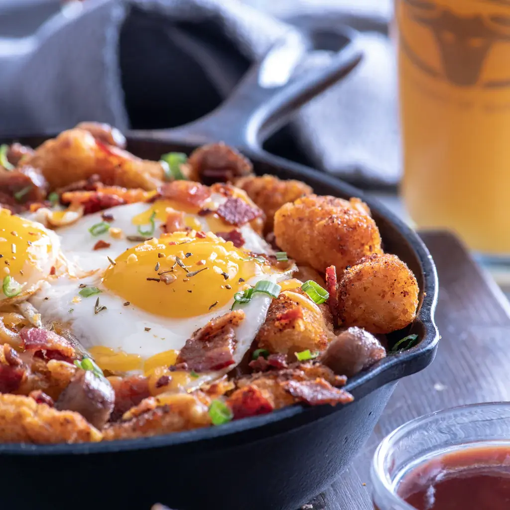 Cast iron pan with roasted potatoes bacon and sunnyside up eggs
