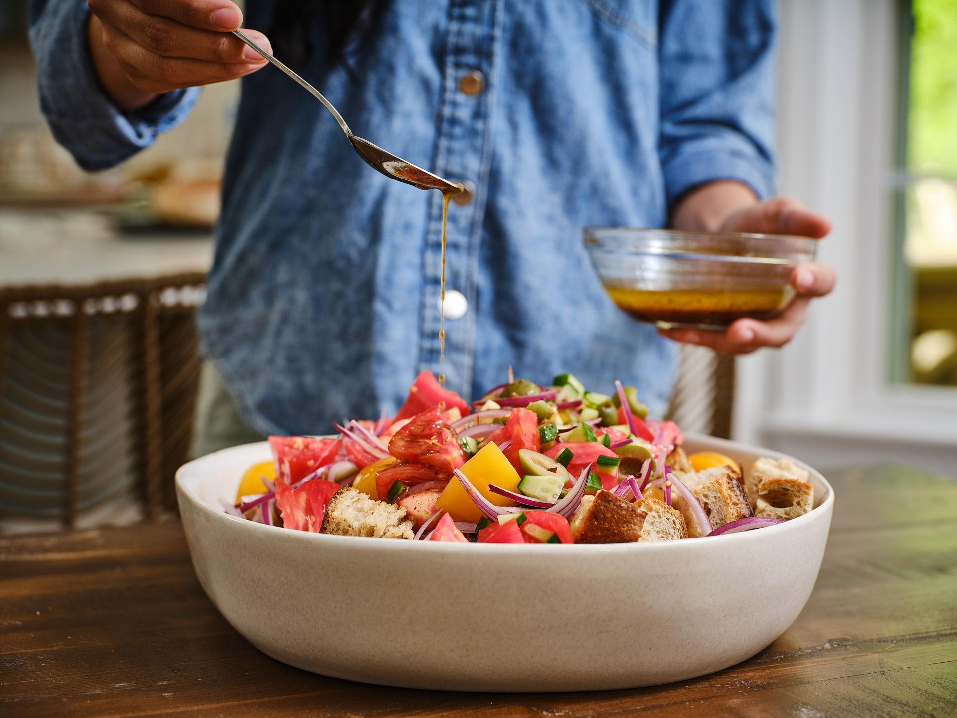 Drizzling vinaigrette on a panzanella salad