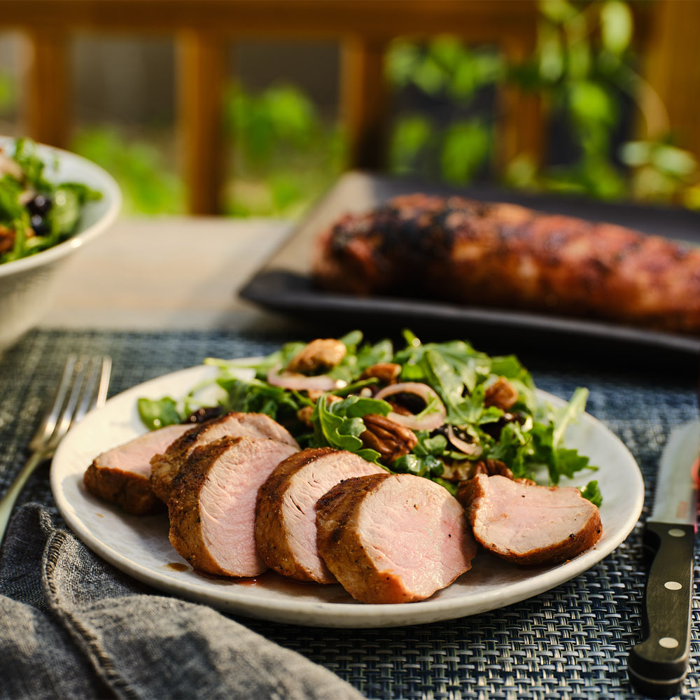 Sliced pork tenderloin served with salad on a plate 