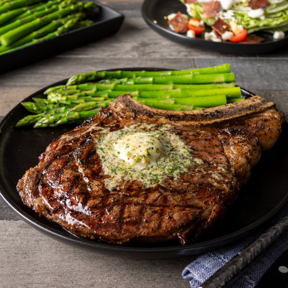 Grilled ribeye on a black plate with asparagus