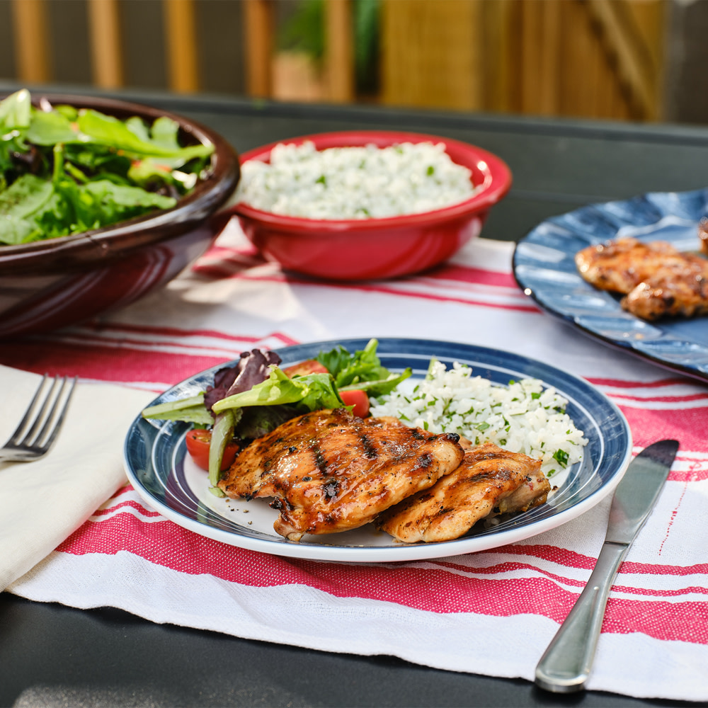 Grilled chicken on a picnic table with rice and salad