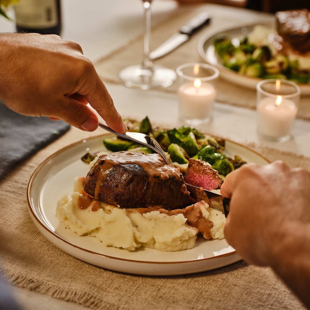Filet mignon and mashed potatoes being cut into on a plate