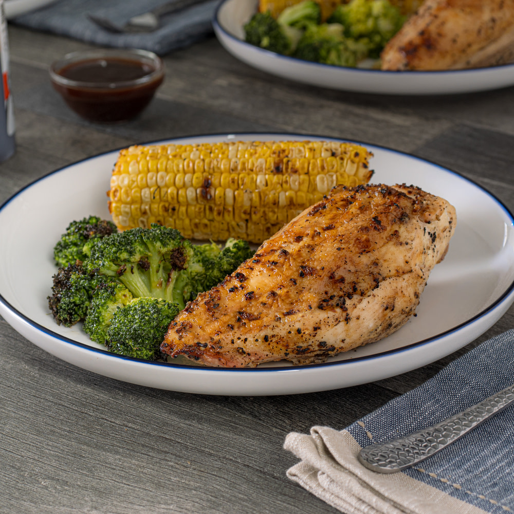 Grilled chicken on white plate with broccoli and corn on the cob
