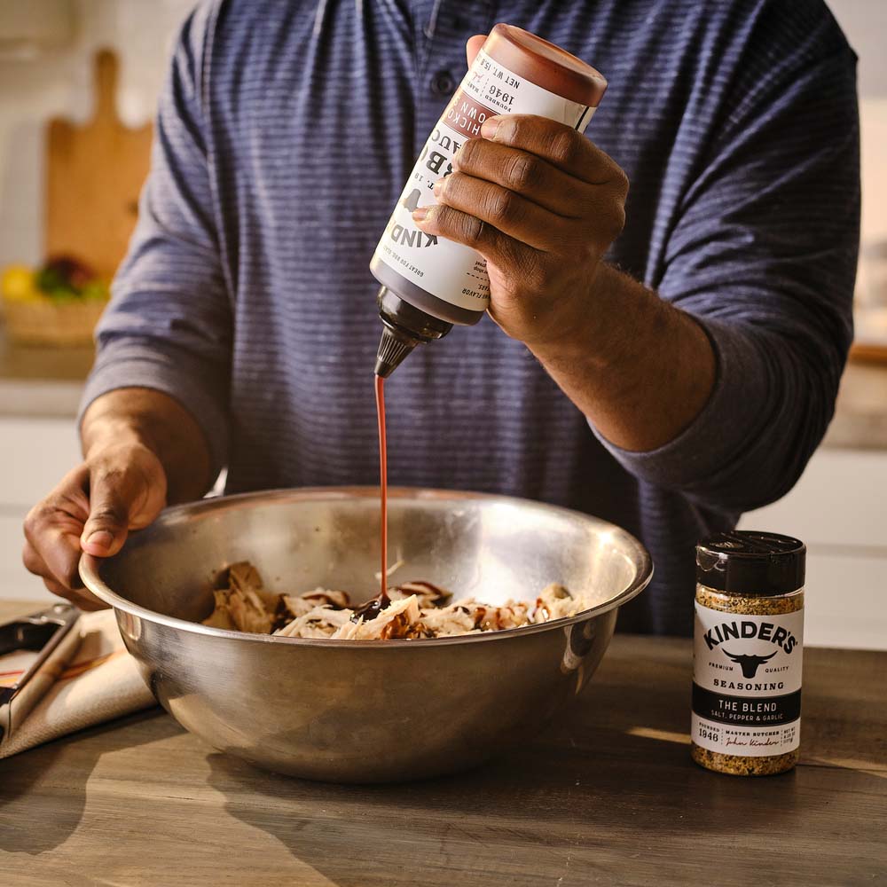 Pulled chicken in a metal bowl with BBQ sauce