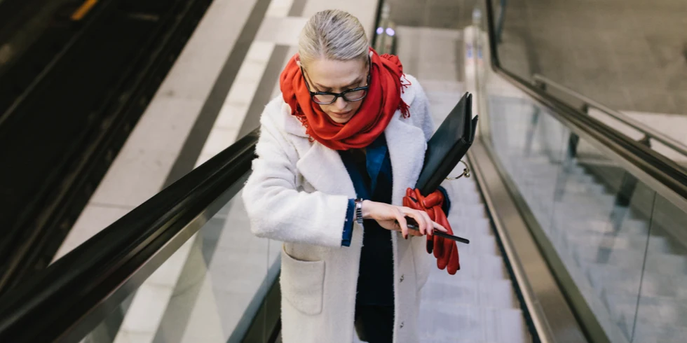 Well-dressed woman with business portfolio standing on a escalator