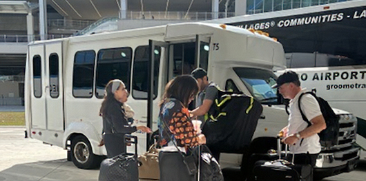 Photo of a group of people boarding a white shuttle.