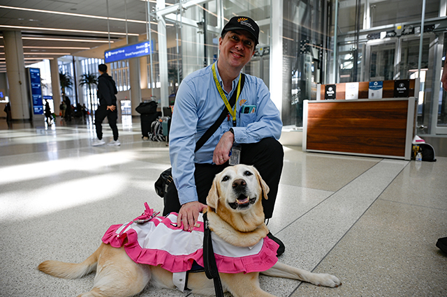 2025 Halloween at MCO photo of a MCO employee with dressed up Paw Pilots dog.