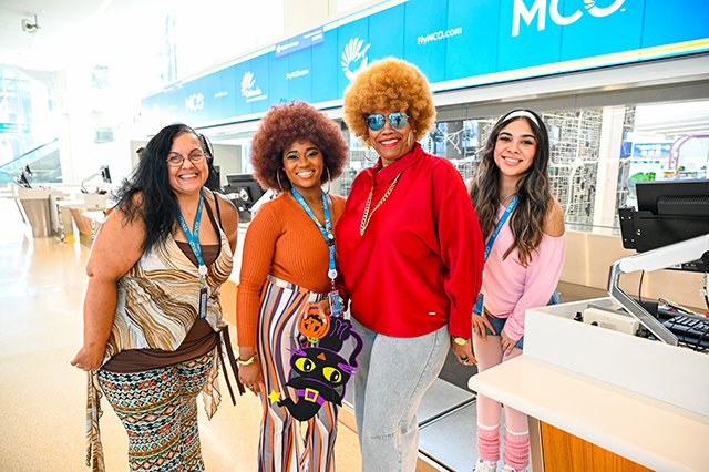 2025 Halloween at MCO photo of four women dressed up in 70's clothing.