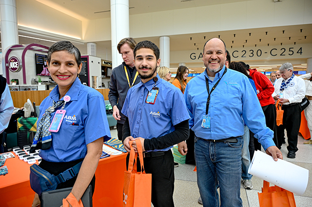 2025 Halloween at MCO photo of three people receiving a MCO orange bag.
