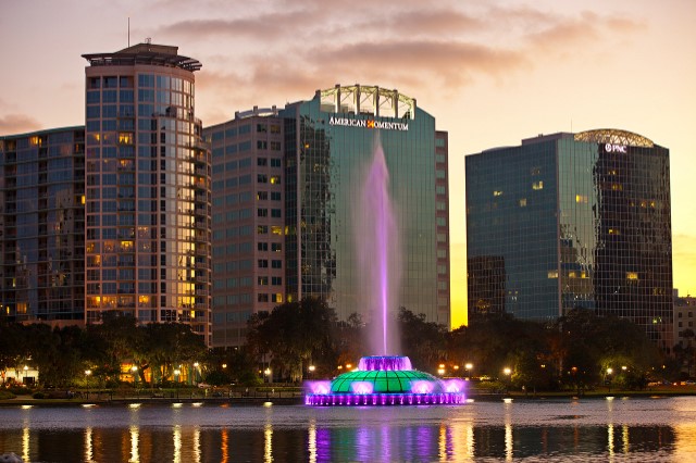 Fountain in Lake Eola with buildings in the background.