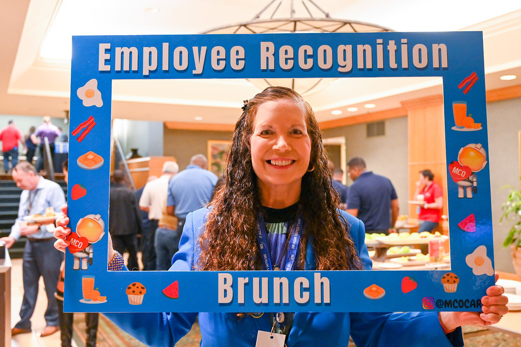 January 2024 Employee Recognition Brunch. Photo of one GOAA employee holding a large frame in front of them. The frame says, "It all starts with me!"