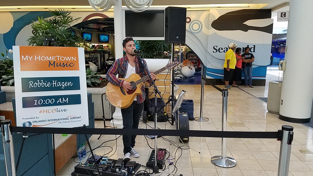 Robbie Hazen May 2017 playing the guitar in a terminal at MCO.