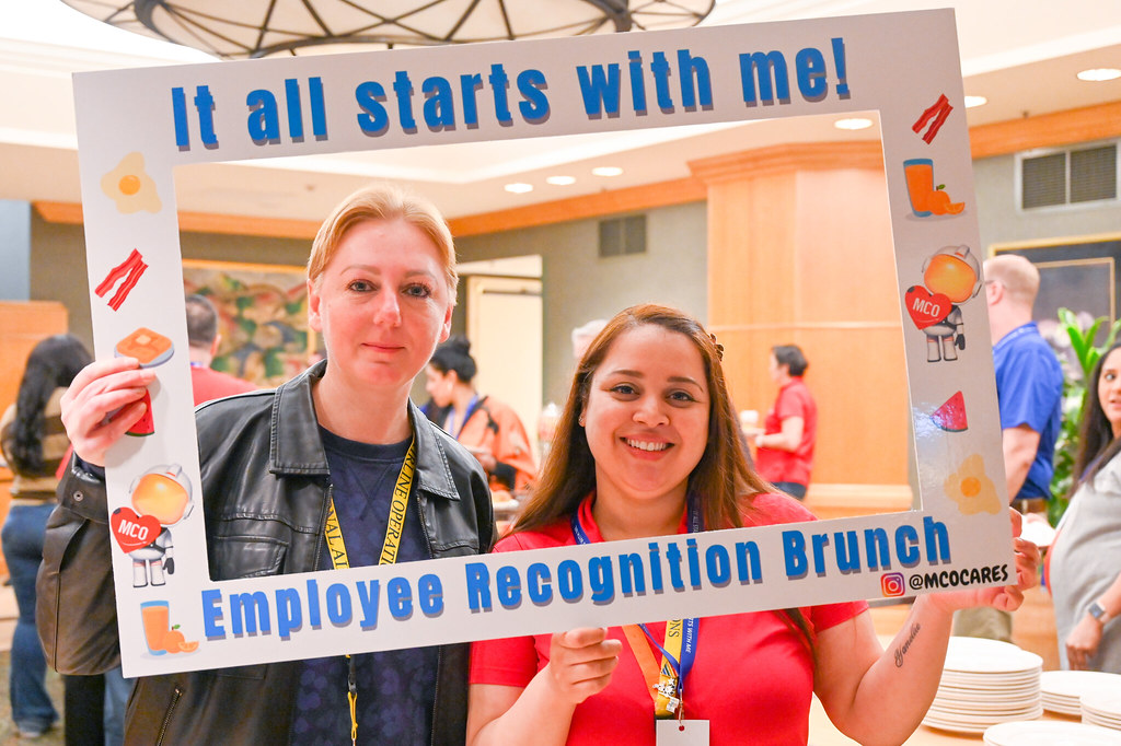 January 2024 Employee Recognition. Photo of two GOAA employees holding a large frame in front of them. The frame says, "It all starts with me!"