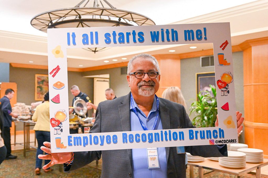 January 2024 Employee Recognition Brunch. Photo of one GOAA employee holding a large frame in front of them. The frame says, "It all starts with me!"