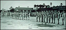 An old 1940 black and white photo of US Army Corps soldiers lined up on the runway of Orlando Air Base.
