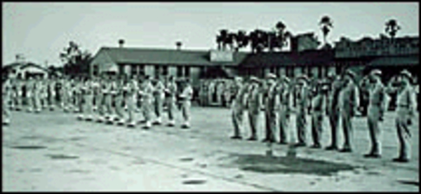 An old 1940 black and white photo of US Army Corps soldiers lined up on the runway of Orlando Air Base.