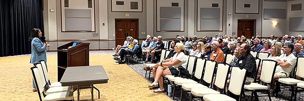 A woman speaker at a podium giving a speech to an audience.