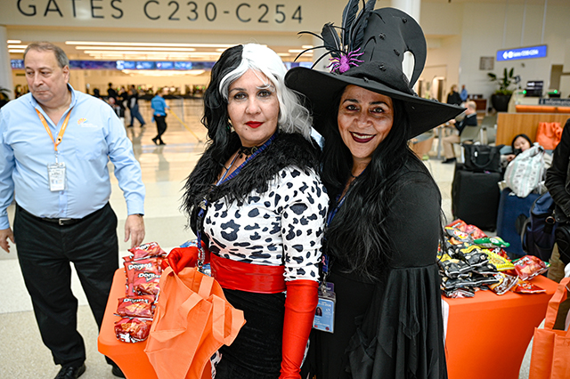 2025 Halloween at MCO photo of two ladies dressed up in costume. The lady on the right is dressed up as Cruella and the one on the right is dressed up as a witch.