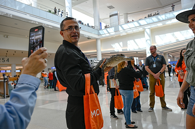 2025 Halloween at MCO photo of people holding orange MCO bags.