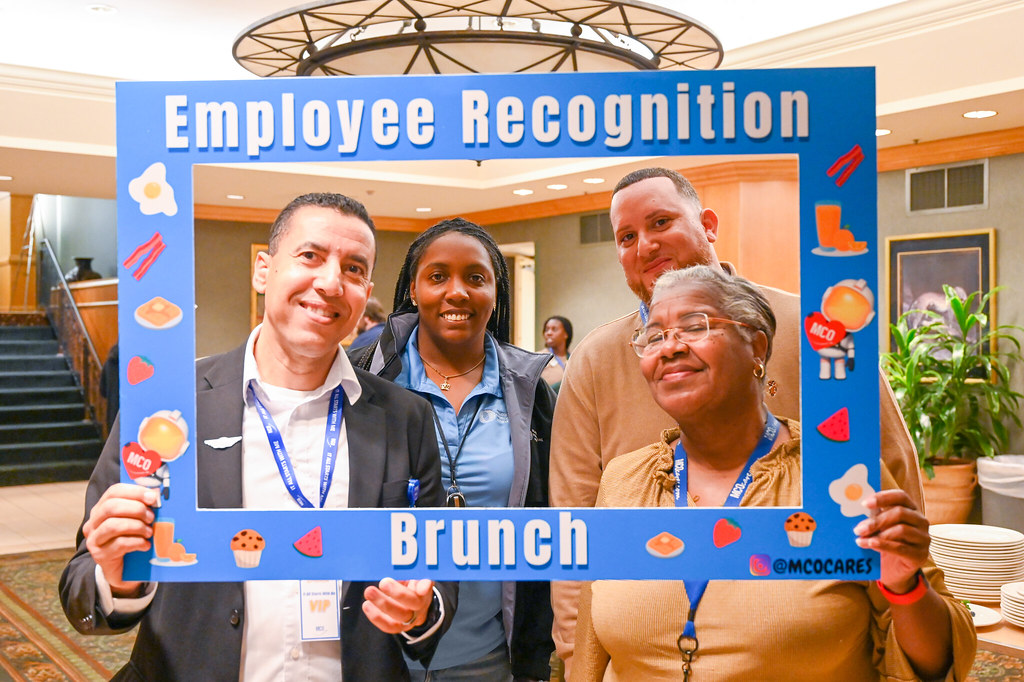 January 2024 Employee Recognition Brunch. Photo of three GOAA employees holding a large frame in front of them. The frame says, "It all starts with me!"