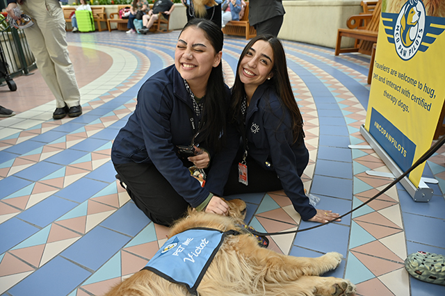2025 World Kindness Day photo of two ladies sitting on the floor smiling with a Paw Pilots dog.