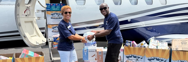 Lance Lyttle and Judith-Ann Jarrette outside in front of a corporate jet helping with the pack the plane event.