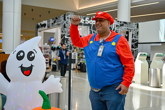 2025 Halloween at MCO photo of a man dressed up as Super Mario raising his right fist.