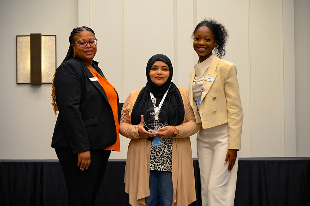 2025 Employee Recognition Brunch photo of three employees. The one in the middle is holding an award.