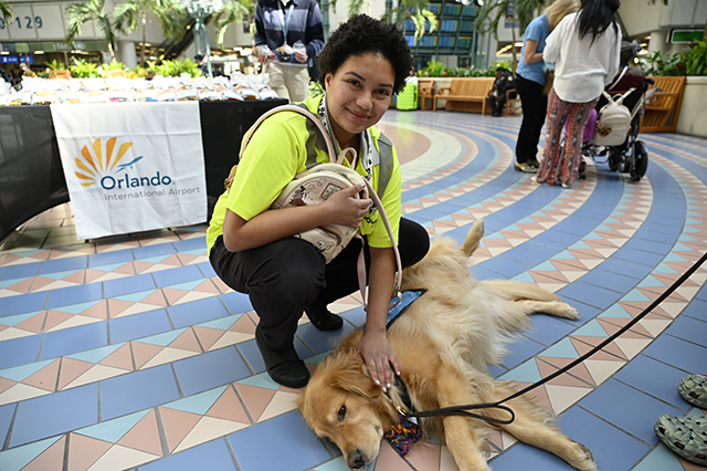 2025 World Kindness Day photo of a young lady petting a Paw Pilots dog which is lying on the floor.
