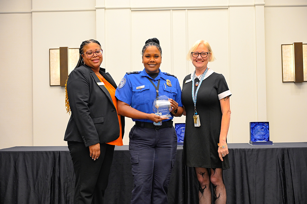 2025 Employee Recognition Brunch group photo of three employees. The one in the middle is holding an award.