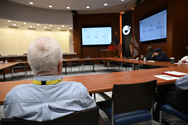 CSAC Culture Team - WORKSHOP Learn and Grow - Compassion Fatigue photo of a GOAA employee sitting at table looking at the speaker at the podium.