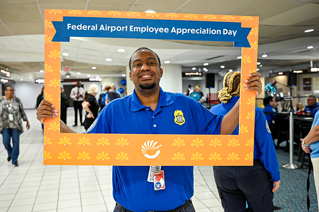 2025 Federal Airport Employee Appreciation Day photo of one federal TSA agent holding a large frame in front that says, "Federal Airport Employee Appreciate Day."