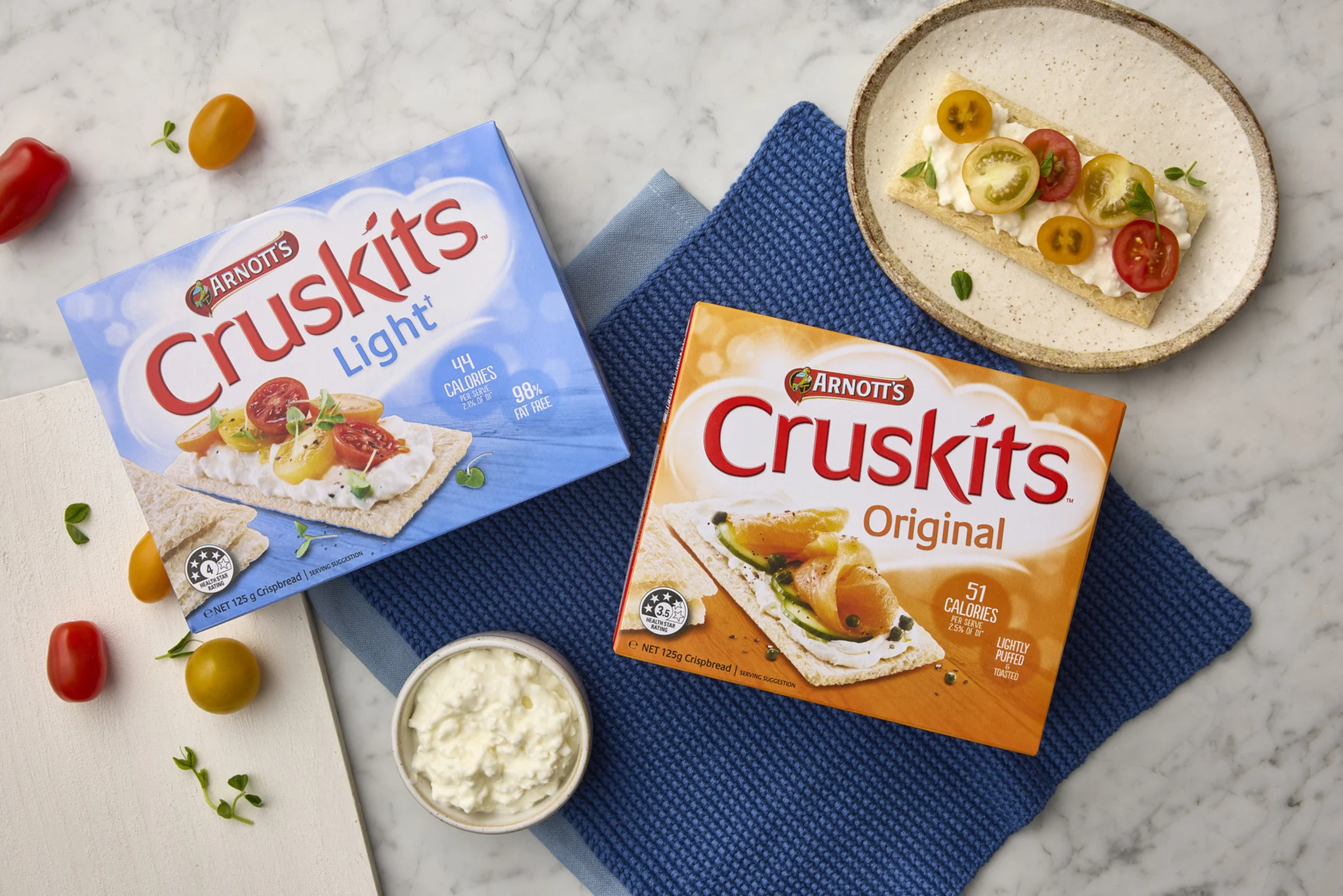 Image of Two Cruskits Packs, with topped Cruskit tomato and cream cheese