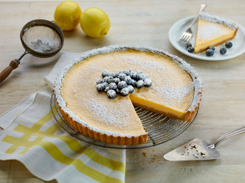 Lemon tart, topped with blueberries and icing sugar