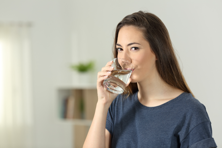 A woman in her living room drinking a glass of water