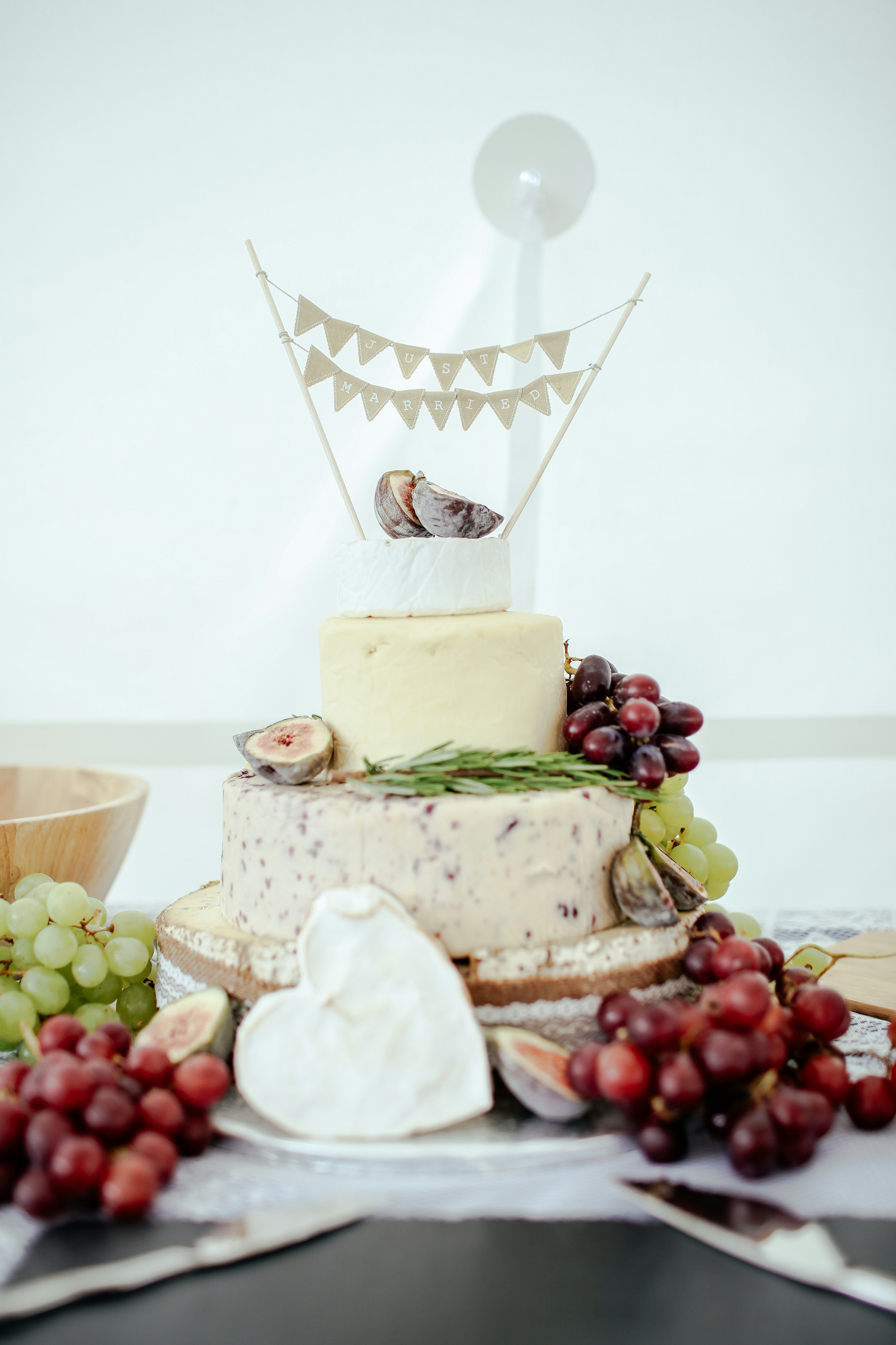 a multi-tiered cake of various chesses with bunches of grapes