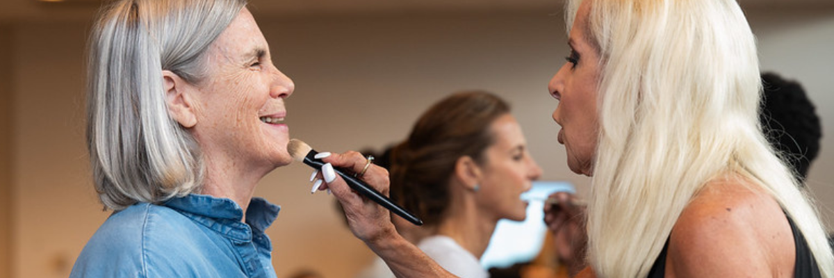 Woman putting foundation powder on another woman's face 